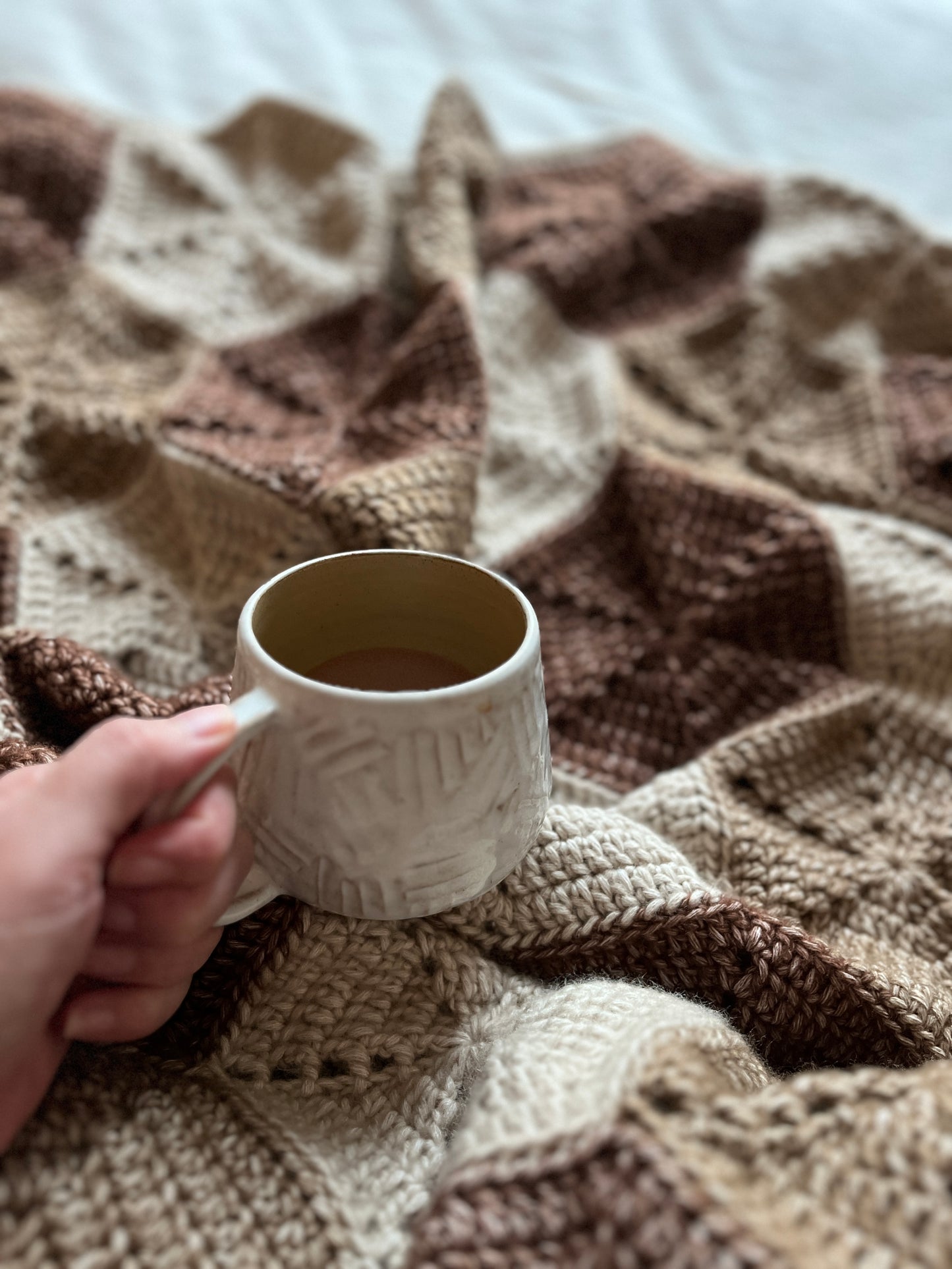 snuggling in a crochet blanket with a cup of coffee , throw blanket, hexagon motifs, cosy warm colours, browns, beiges, handmde, cotton-blend, wool-sensitive
