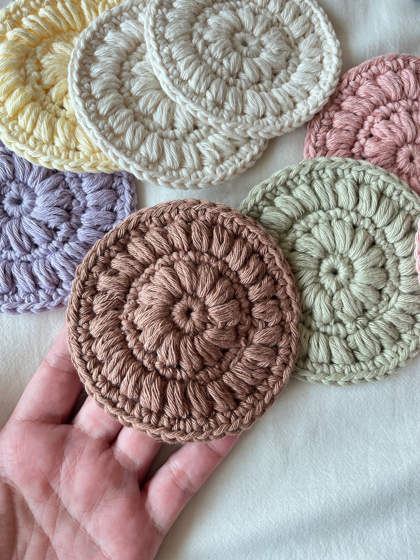 Hand holding a brown crocheted face scrubby