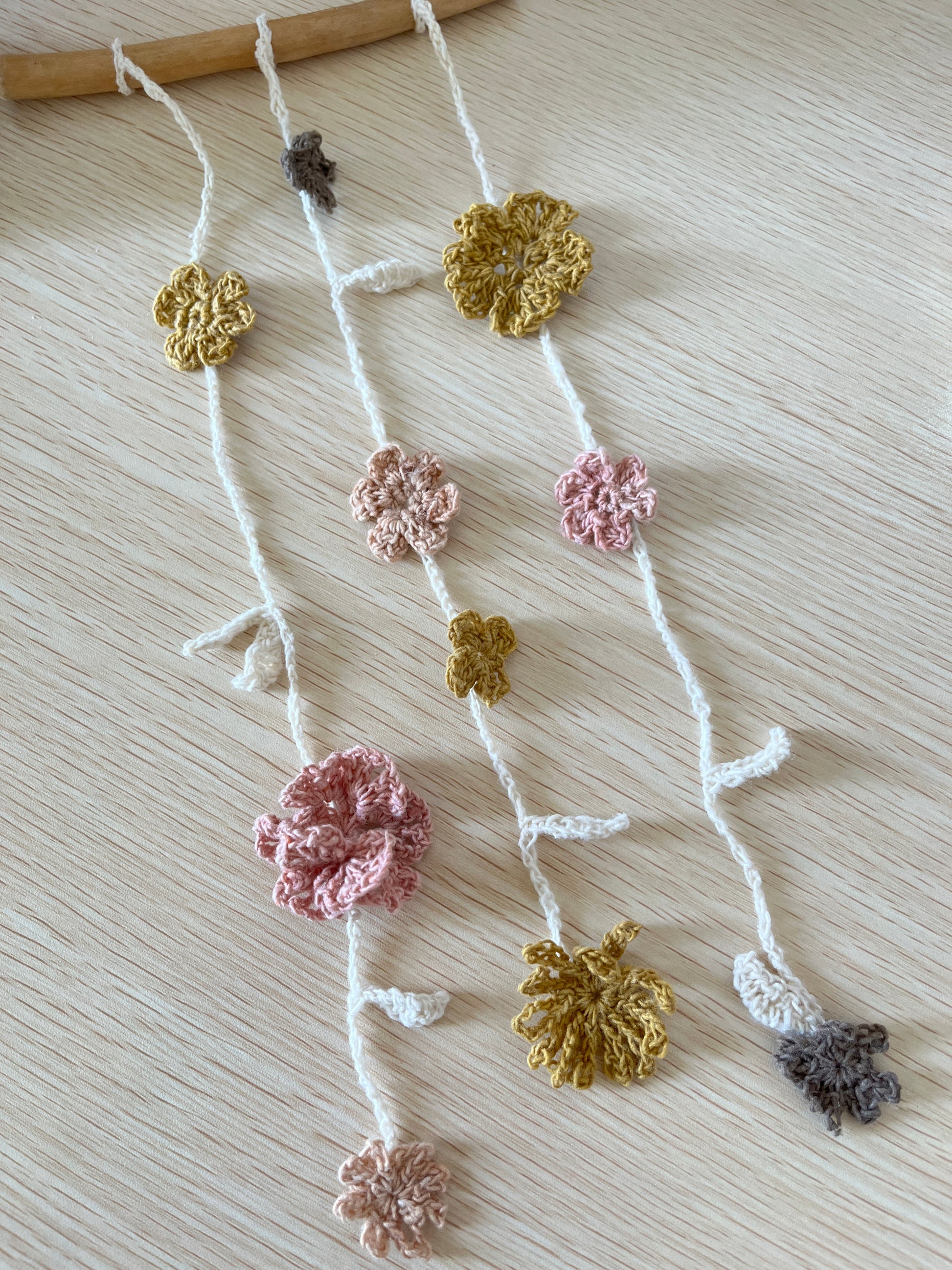 Decorative crochet strings of flowers on a light wooden surface