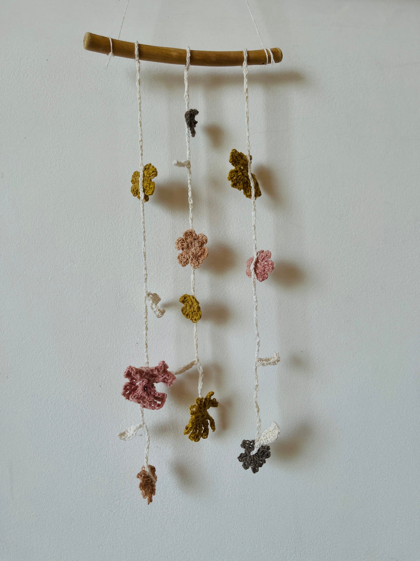 Decorative hanging mobile with crocheted flowers on a white wall 