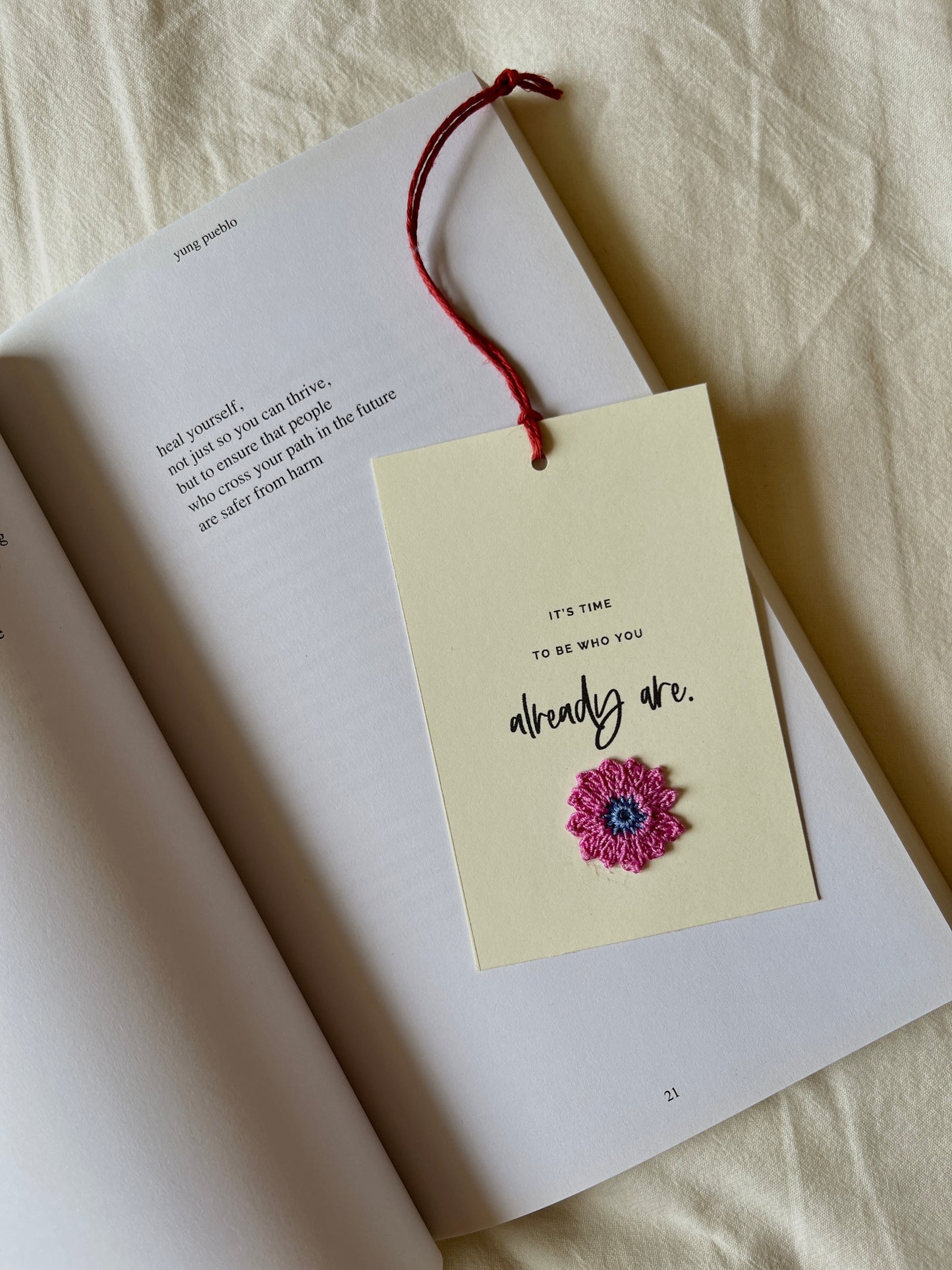 inspiration notecard in cream used as a bookmark, placed on an open page in a book. eco friendly bookmark, crochet motif, sustainable gifting ideas, inspiring notecards, affirmation cards