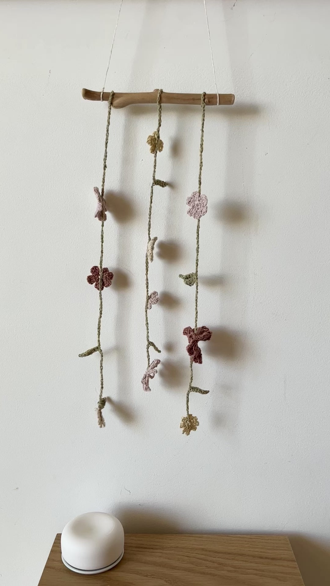 strings of crochet flowers mounted as a wall hanging, swaying gently in the breeze
